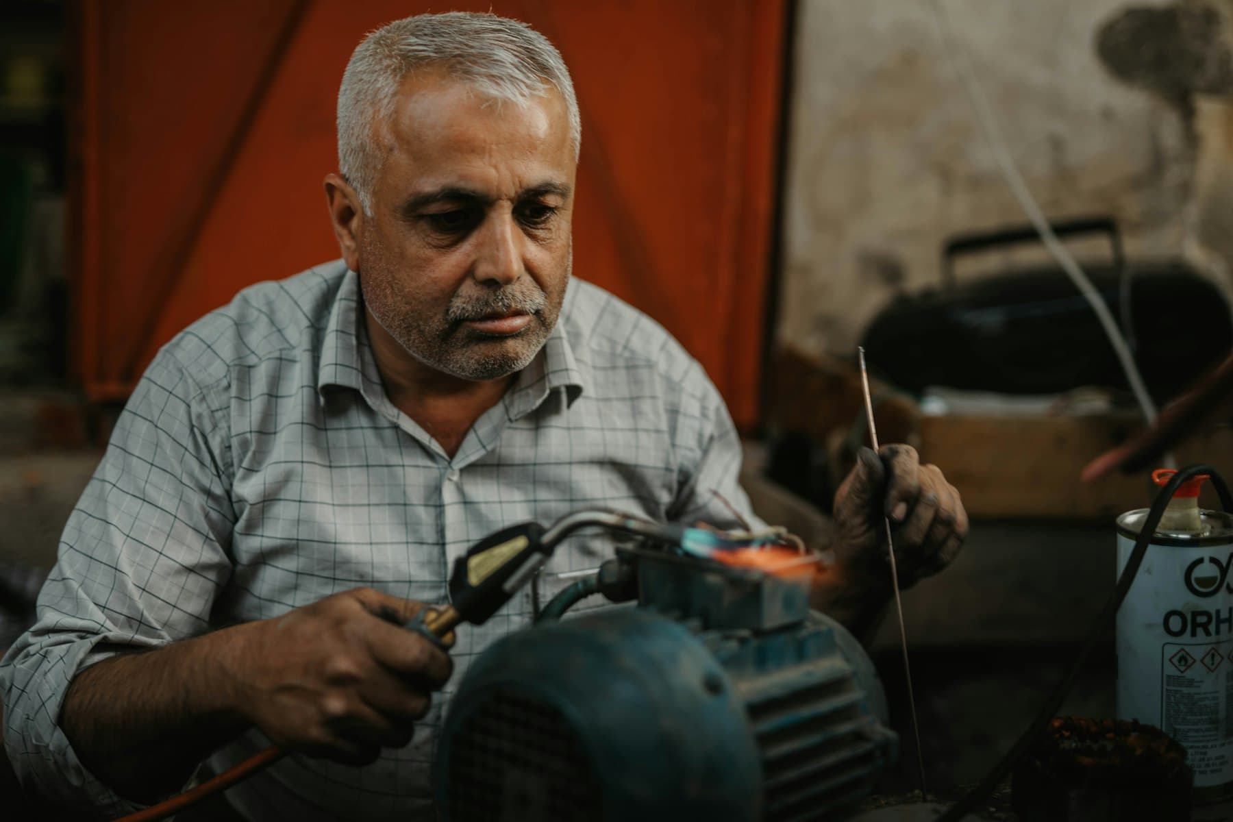 A repair technician brazing a motor at his workbench.