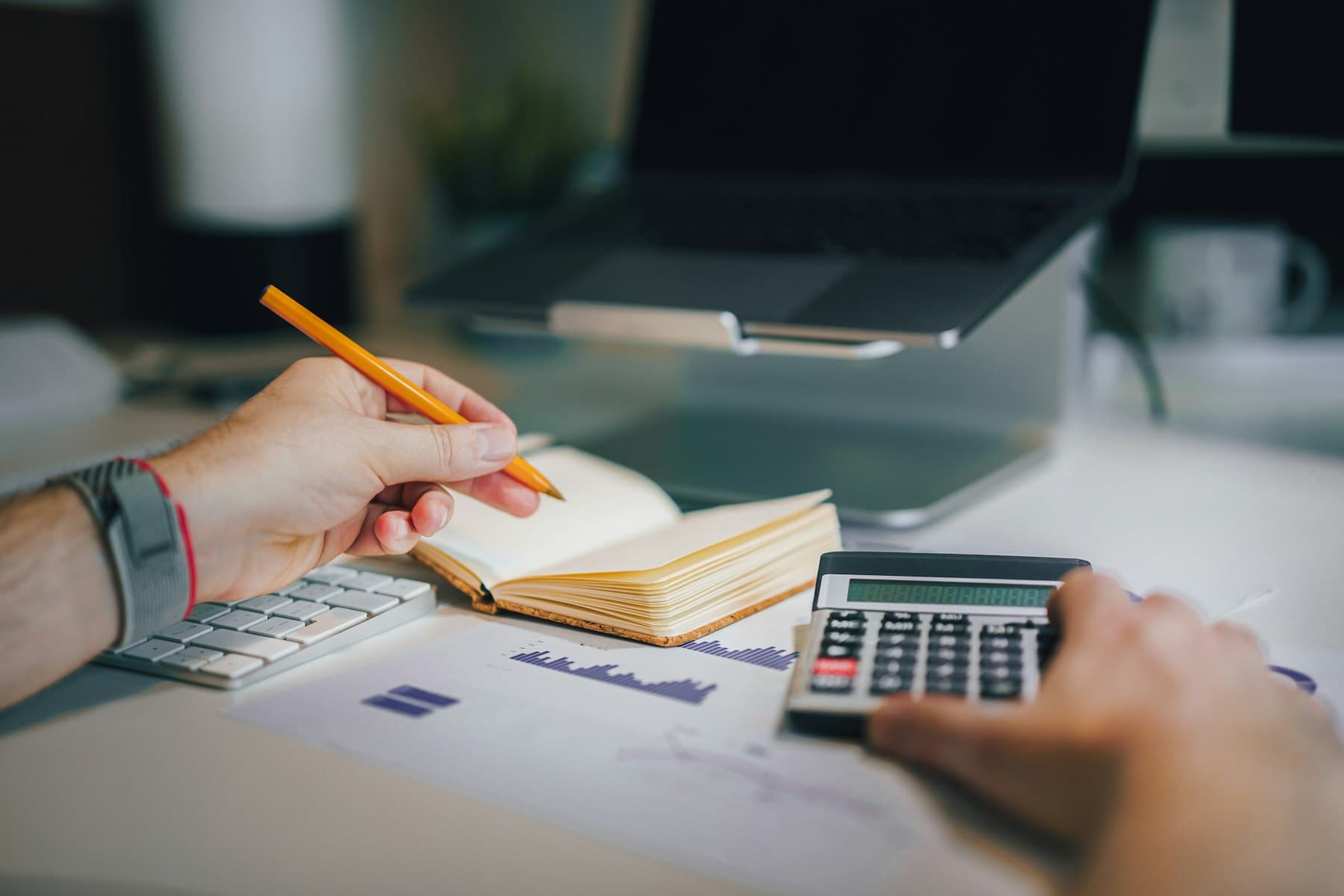 A bookkeeper working with a calculator and a notebook at a desk.