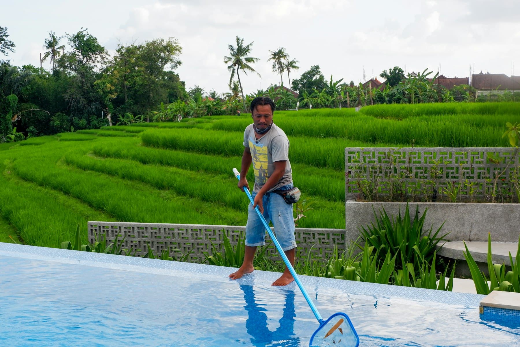 A pool technician skimming the water with a net.