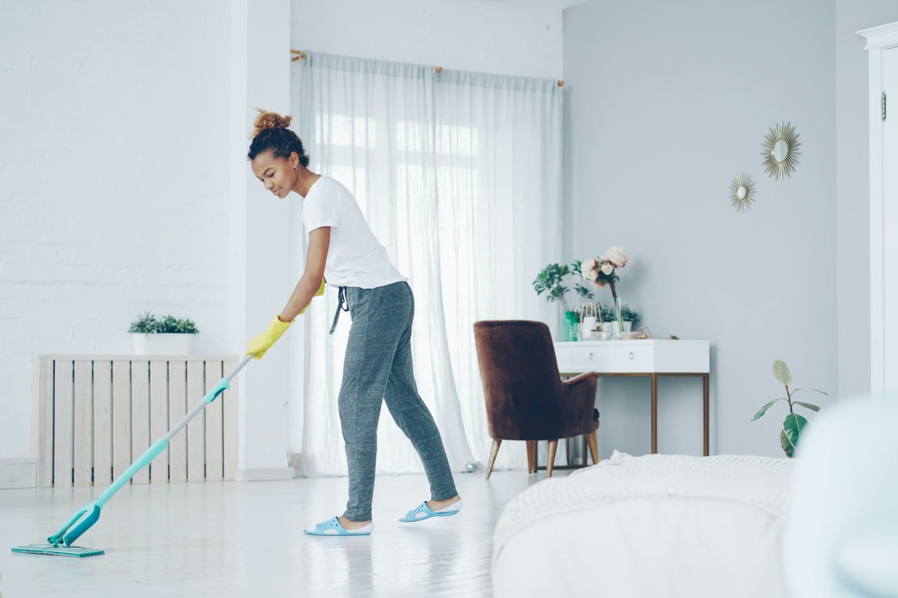 A cleaner mopping the floor of a bright living room.